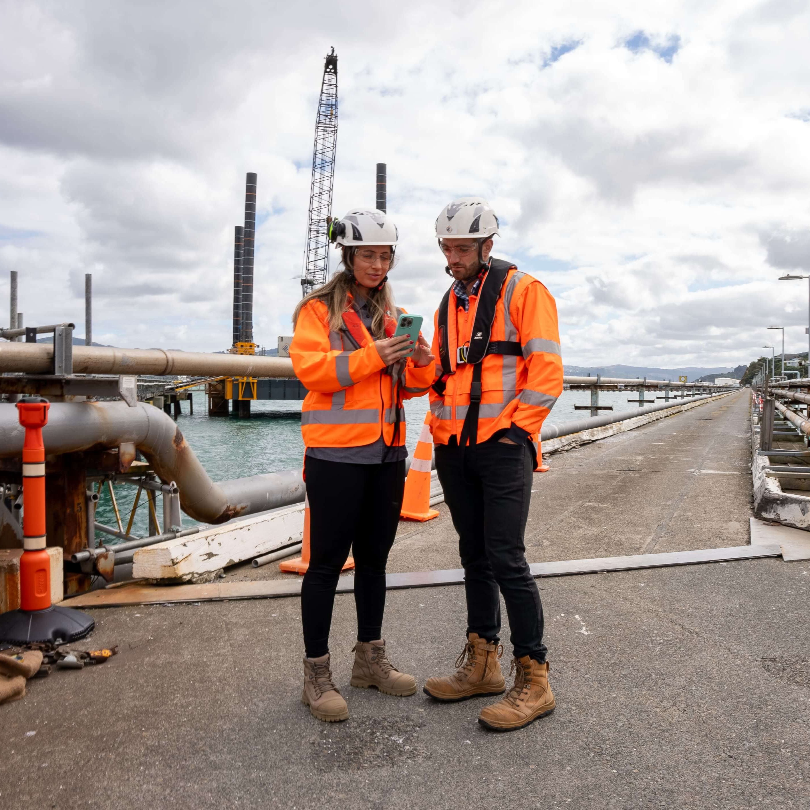 Two construction workers looking at a phone in a construction site